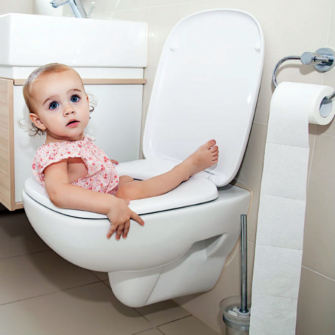 Toddler playfully stuck in the toilet, looking towards the camera for blog "Bathroom Safety for Children"